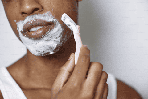 African American man shaving with a pink razor