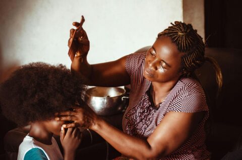 black woman combing child's hair