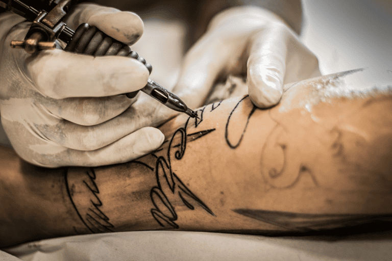 Hands tattooing arm