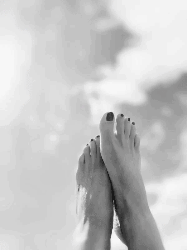 Black and white photo of feet against sky background