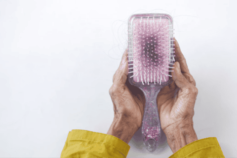 Hands holding hairbrush with hair strands