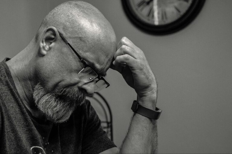 Black and White Image of Bald Man with Hand on Head