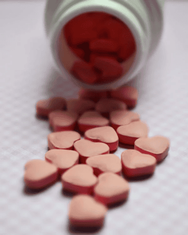 Pink heart-shaped pills spilling out of bottle